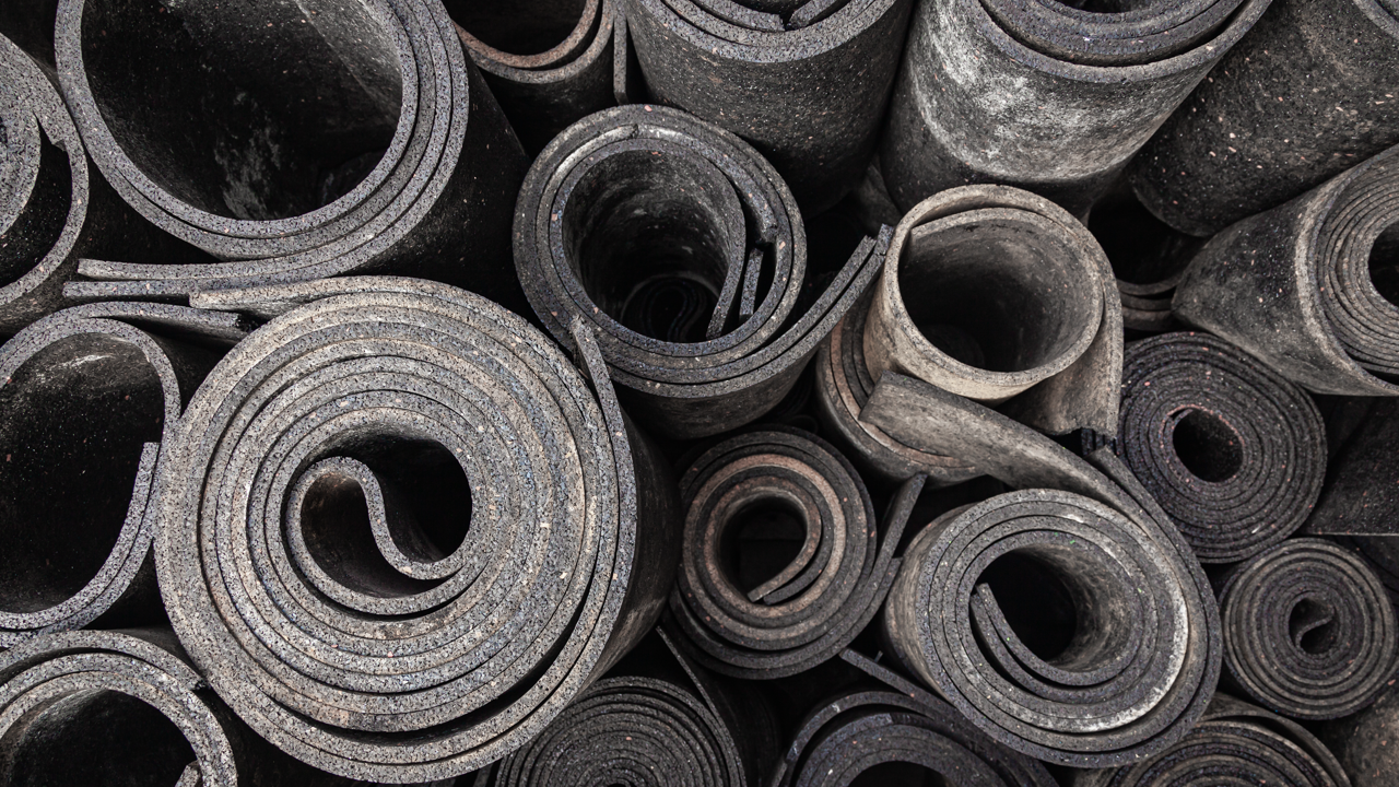 Rolls of rubber material stacked in storage — the tread rubber and cushion gum stock an in-house retread line consumes on every cure