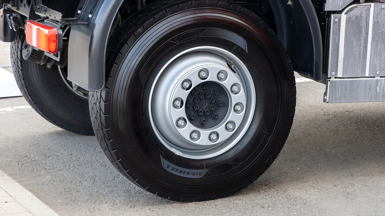 Close-up of a commercial truck tire and wheel, sidewall tire size markings visible — the same sidewall a retreader must label under NHTSA rules