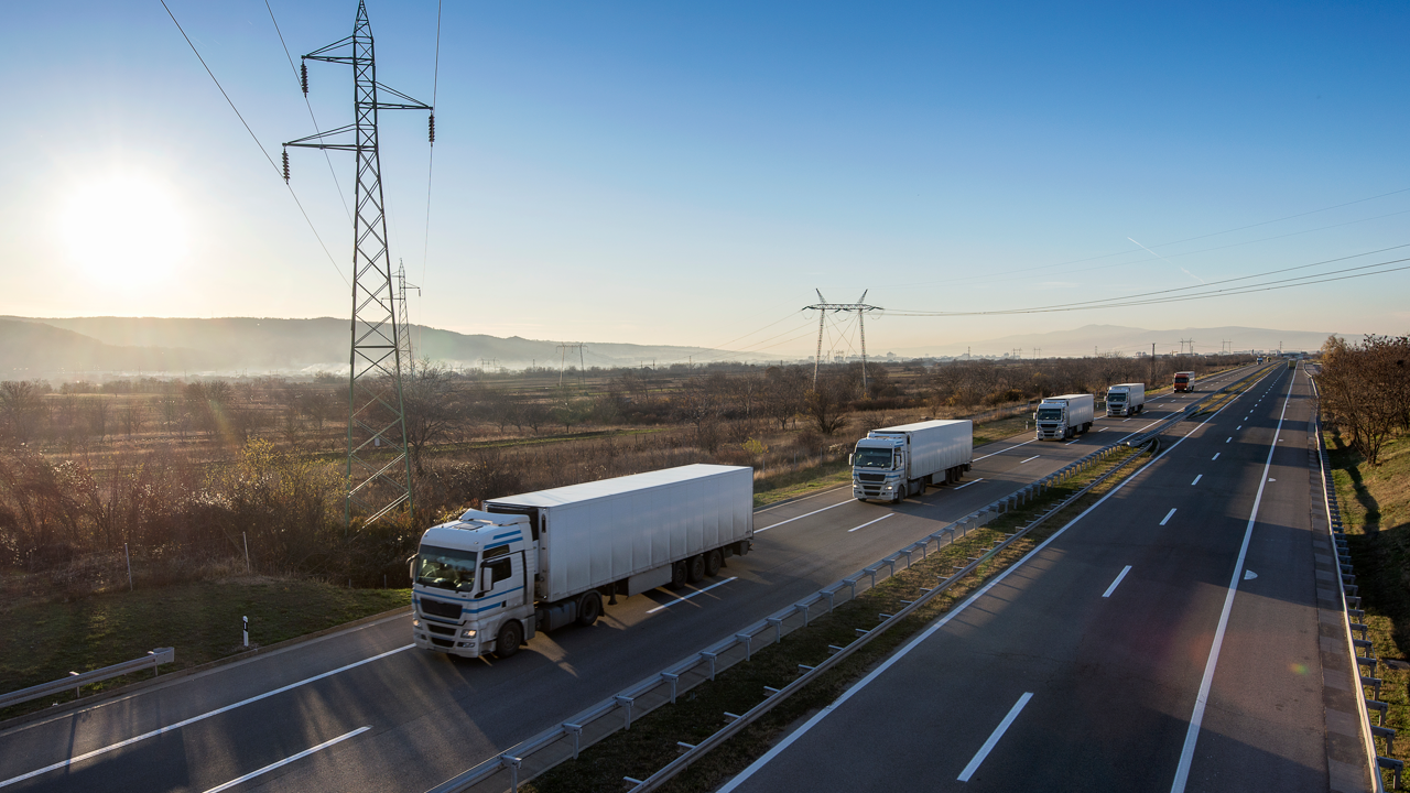 Convoy of commercial fleet trucks on a highway — fleet size and tire volume are the real inputs to an in-house retreading payback calculation