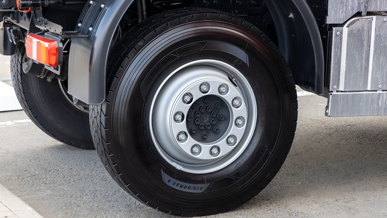 Close-up of a commercial truck's rear tire and wheel, sidewall tire size marking visible — the kind of defect a driver's pre-trip walkaround is meant to catch
