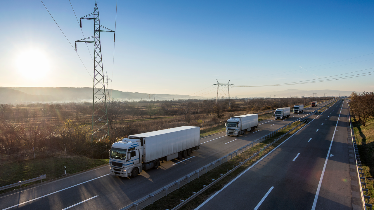Fleet of commercial trucks on the highway — the fuel and manufacturing footprint of tires scales directly with fleet size