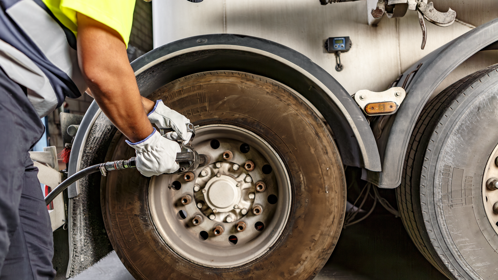 Technician using a rotary repair tool to skive out an injury on a tire casing at a repair bench