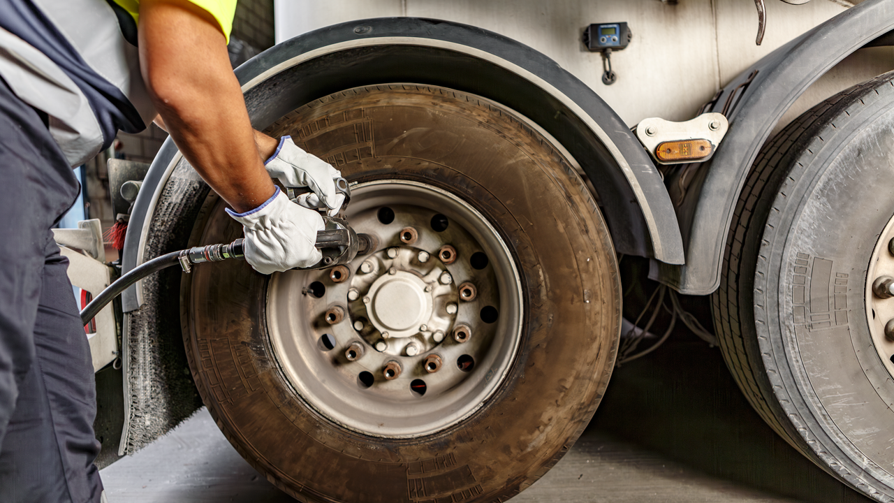 Technician repairing and inspecting a commercial truck tire casing in a shop — skiving repairs casing damage before the tread is applied