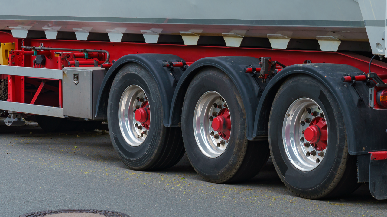 Wide-base single tire mounted on a commercial trailer axle, replacing a traditional dual tire setup